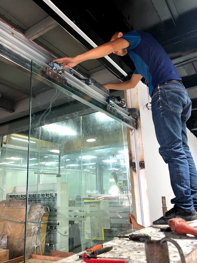 Kỹ thuật viên lắp đặt hệ thống ray trượt cho cửa kính cường lực tại công trình nội thất
